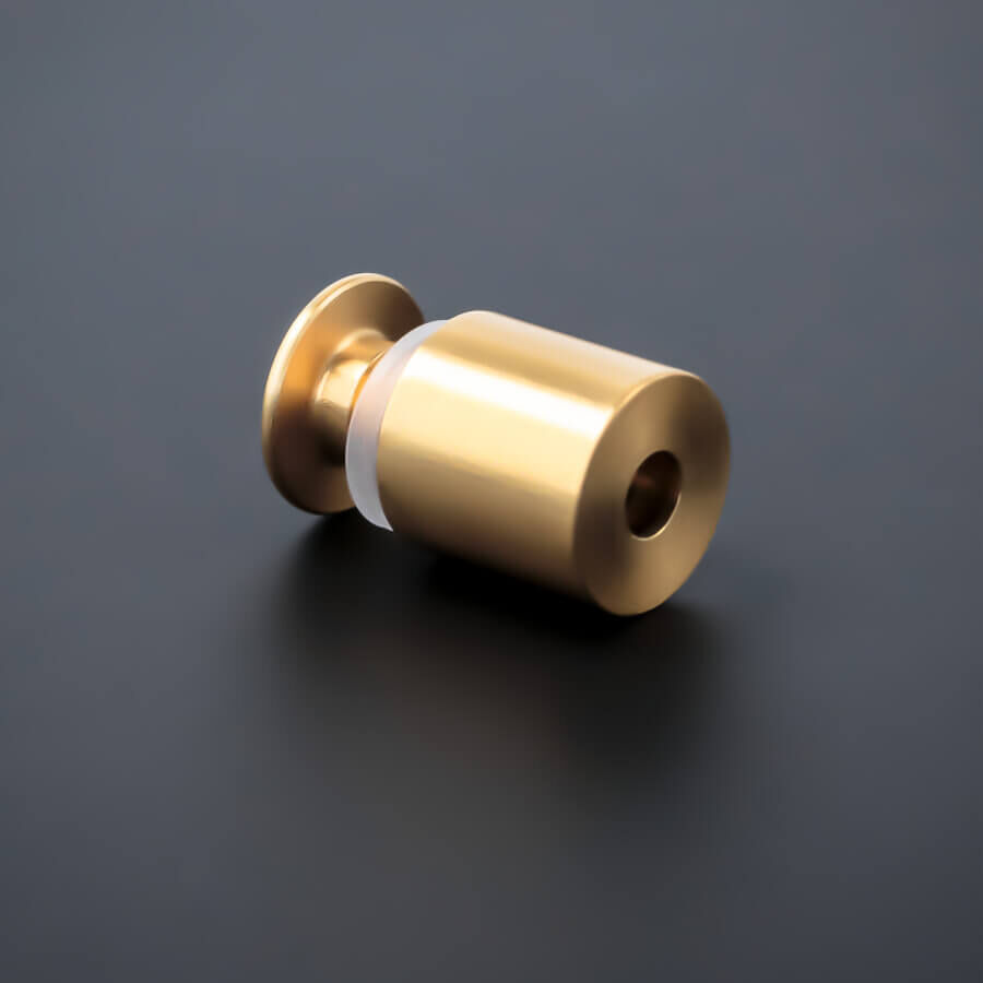 Abstandshalter schraubbar Messing Ø15 mm liegend auf dunklem Untergrund